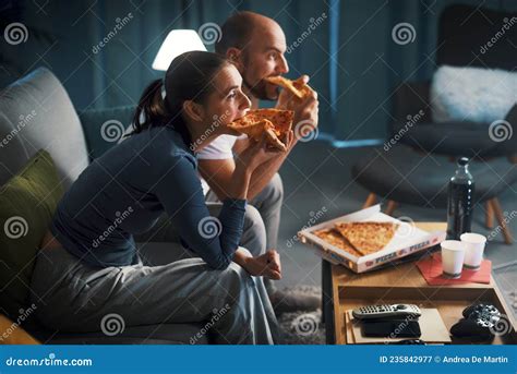 pareja feliz sentada en el sofá y comiendo pizza juntos imagen de archivo imagen de hombres