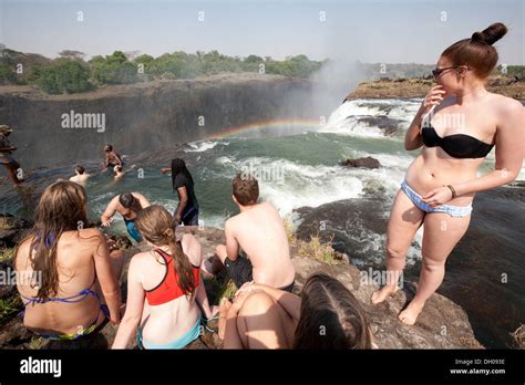 tourists swimming in devils pool at the edge of victoria falls livingstone island zambia