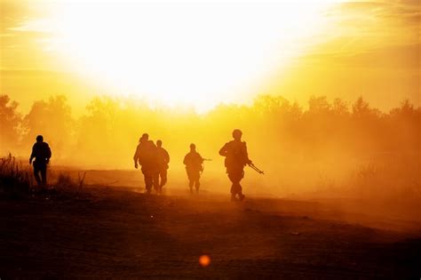 Military Or Soldier Silhouettes On Sunset Sky Background Fully Equipped And Armed Soldier