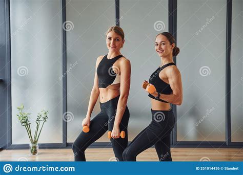 Uses Dumbbells Two Women In Sportive Wear And With Slim Bodies Have Fitness Yoga Day Indoors