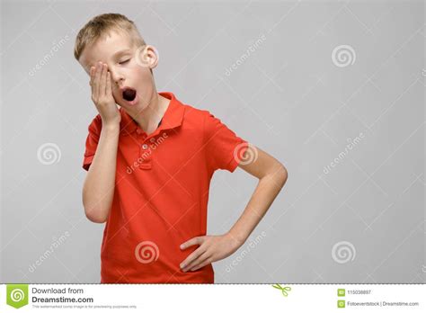 Portrait Of Blonde Caucasian Sad Little Boy In Orange T Shirt Wanting