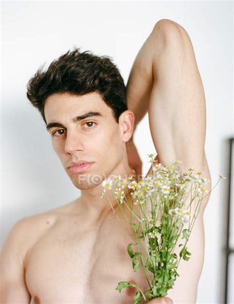 Side View Of Young Shirtless Guy With Fresh White Flowers In Hands