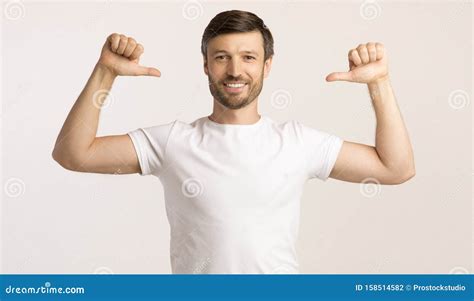 Guy Pointing Thumbs At Himself On White Studio Shot Stock Photo