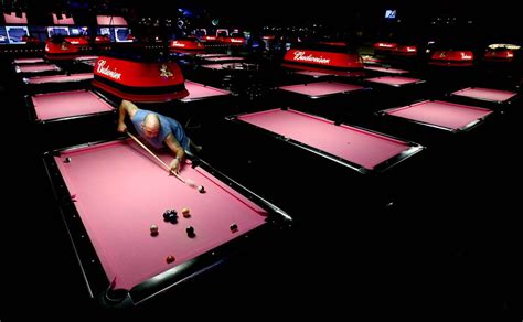 A Man Is Playing Pool In A Large Room Full Of Red And Black Billiards