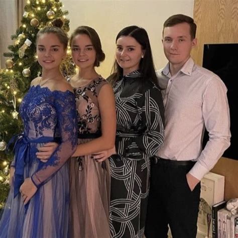 Four People Standing Next To Each Other In Front Of A Christmas Tree