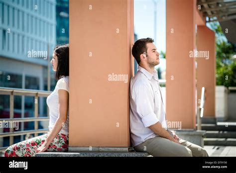 Couple Having Problems Two People Sitting On Opposite Side Of Big Collumn In Street Stock