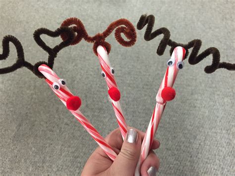 Three Candy Canes Decorated With Reindeer Noses And Nose Holes Are Held