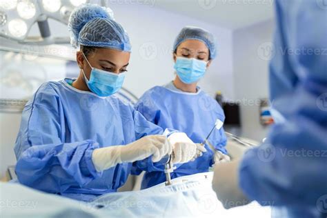 Concentrated Female Surgeon Performing Surgery With Her Team In Hospital Operating Room Medics