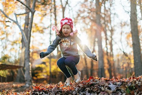 Cute Young Girl Jumping In A Bed Of Leaves By Stocksy Contributor