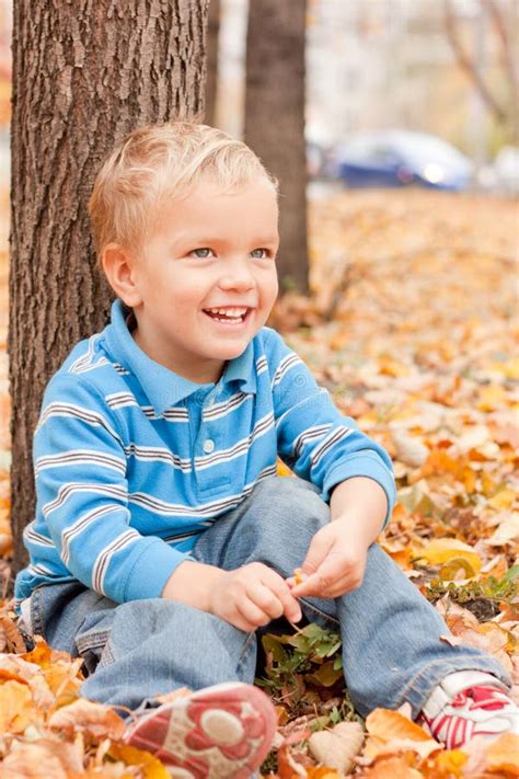 Cheerful Boy Sitting On Yellow Foliage Stock Photo Image Of Little