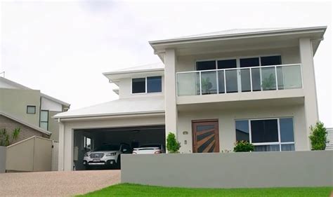 A Car Is Parked In Front Of A Two Story House With An Attached Garage Door