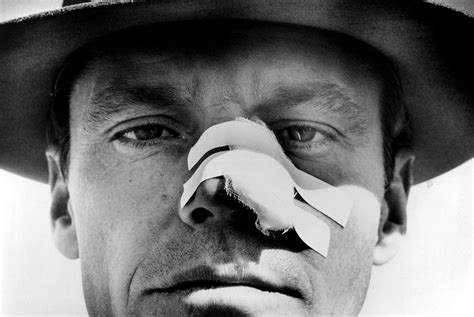 a man wearing a hat and holding a piece of paper to his nose with the word chinatown on it