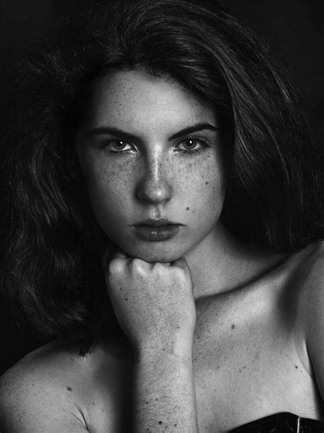 A Black And White Photo Of A Woman With Freckles On Her Face Looking At