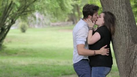 Two Young People Kissing In A Public Park Under A Tree Couple In Love