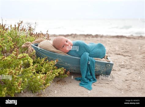 Three Week Old Newborn Baby Boy Swaddled In A Blue Wrap And Sleeping