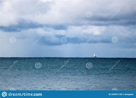 Sailing Yacht Boat On The Sea On Horizon Under Stormy Sky With Clouds