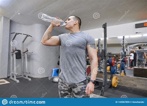 Young Strong Muscular Man In Gym Drinking Water From Bottle Stock Image