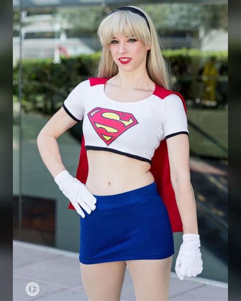 A Woman Dressed As A Supergirl Posing For The Camera With Her Hands On Her Hips