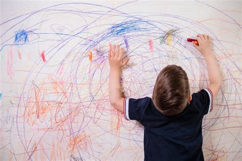 Premium Photo The Child Draws On The Wall With A Crayon The Boy Is