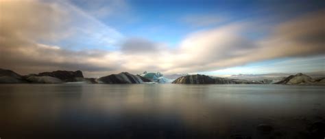 Online Crop Body Of Water And Mountains Under White And Blue Cloudy