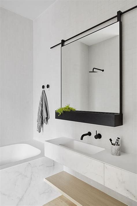 Brighten up your bathroom mirror with a gold frame against a white wall. 16 Perfect Marble Bathrooms with Black Fixtures