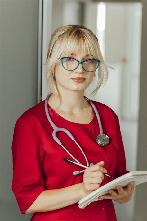 Young Blonde Doctor In A Red Uniform With A Stethoscope A Doctor With