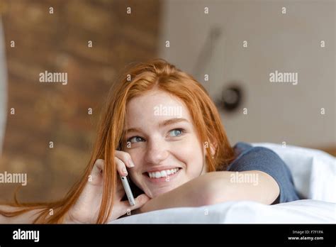 Portrait Of A Happy Redhead Woman Lying On The Bed At Talking On The