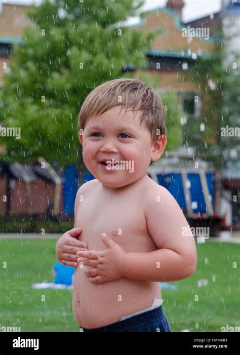 Happy Boy Is Cooling Off As He Plays In A Sprinkler Stock Photo Alamy