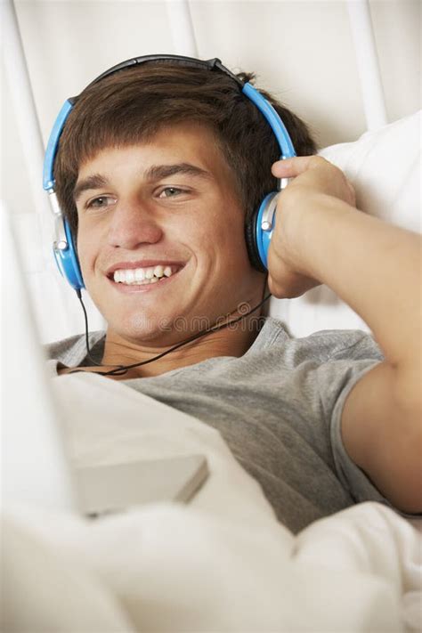Teenage Boy Using Laptop And Headphones In Bed At Home Stock Photo