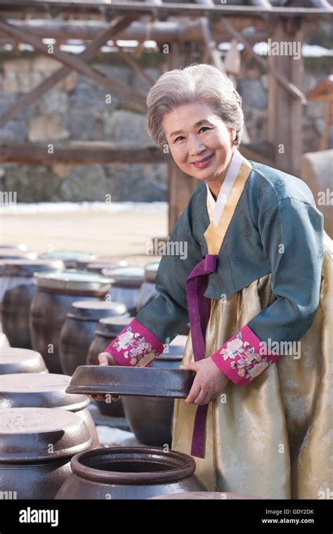 Smiling Old Woman In Traditional Korean Clothes Holding Lid Of Crock