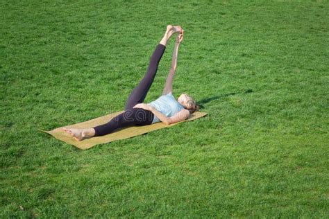 Fit Lady Practicing Yoga Asans On The Yoga Mat Laying In Gren Grass