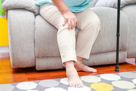 Asian Elderly Woman With Knee Pain Sit On The Sofa In The House Stock