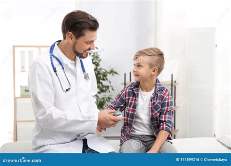 Doctor Checking Little Boy`s Pulse With Medical Device Stock Photo