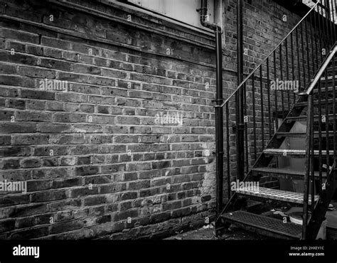 A Old Run Down Brick Alleyway With A Iron Stairway In Black And White