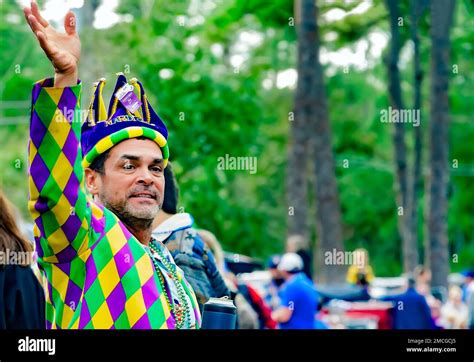 A Man Wearing A Mardi Gras Costume Waves During The Krewe De La