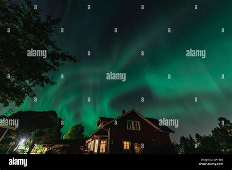 Dancing Northern Lights Aurora Borealis In Autumn Over Wooden House