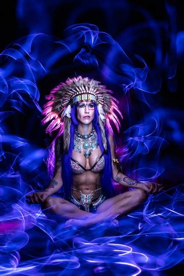 premium photo girl dressed as an indian with feathers on her head poses in the dark for