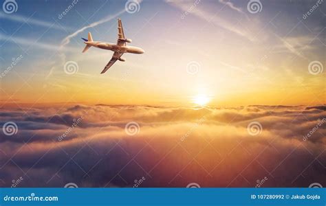 Commercial Airplane Jetliner Flying Above Clouds In Beautiful Sunset