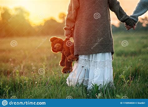 Baby Girl Holds A Teddy Bear In His Hand At Dawn In The