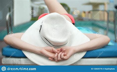 An Unrecognizable Slim Busty Woman In A Big White Hat And A Pink Bikini Is Lying On A Chaise