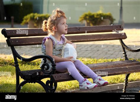 Little Girl Sitting On The Bench Stock Photo Alamy
