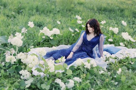Beautiful Woman In Blue Dress On Grass With White Flowers Stock Photo