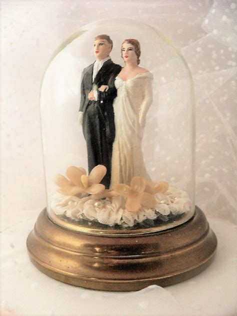 A Wedding Cake Topper Under A Glass Dome