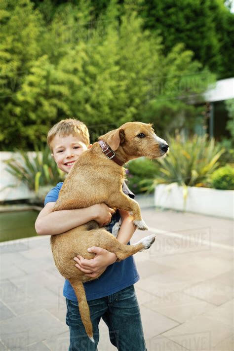 Smiling Boy Holding Dog Outdoors Stock Photo Dissolve