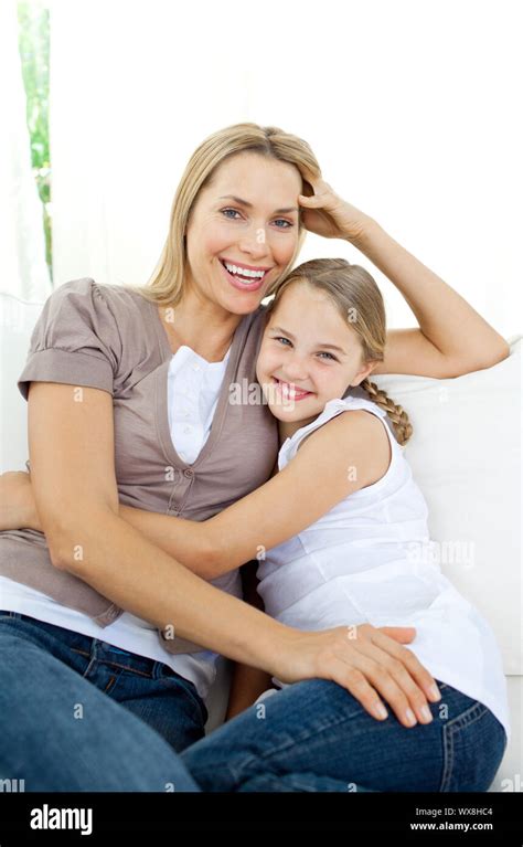 Beautiful Little Girl Hugging Her Smiling Mother On The Sofa Stock