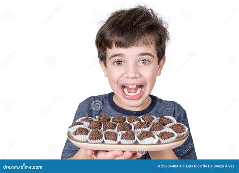 9 year old brazilian holding a tray with several brazilian fudge balls and facing the camera