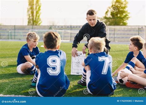 Young Coach Teaching Kids On Football Field Football Coach Coaching