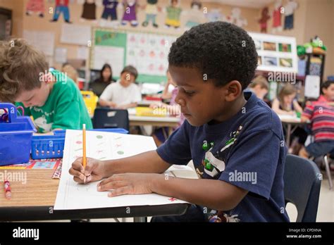 African American Male Kindergarten Student Works At His Desk During
