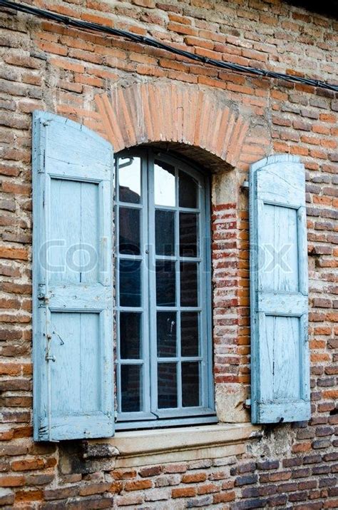 Traditional French Window With Blue Shutters On The Brick Facade