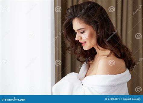Smiling Brunette Young Woman With Hairstyle In A White Bathrobe Posing Near Window Stock Image